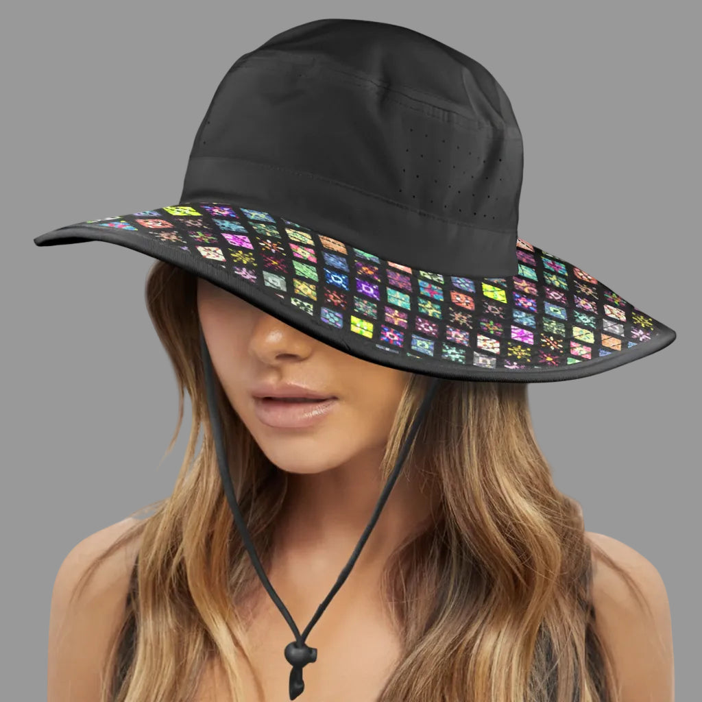 A woman wearing a wide-brim black sun hat with a colorful geometric pattern on the brim, shown against a plain white background.